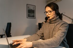 Woman in a call center providing customer support with a headset and laptop.